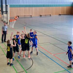 Eine Gruppe von Kindern spielt Basketball in einer Turnhalle.